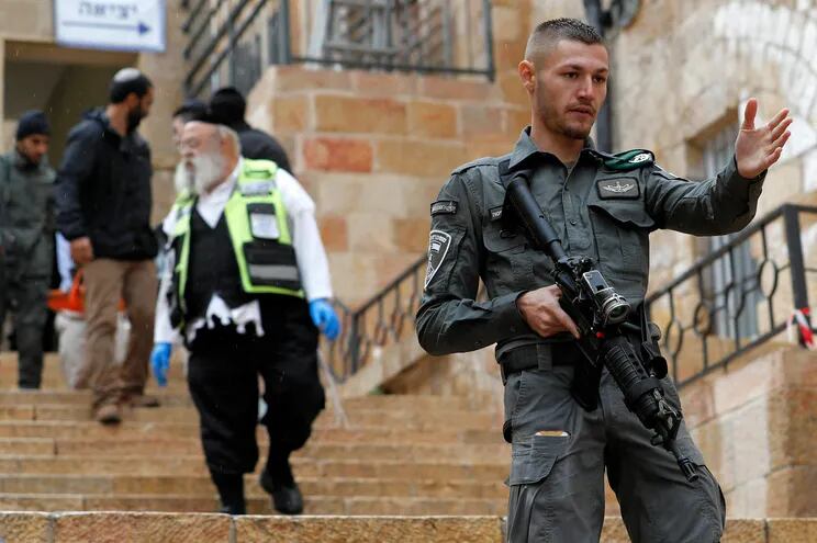Fuerzas de seguridad israelíes aseguran el área para que los paradamédicos puedan retirar el cuerpo de una las de víctimas del tiroteo en la ciudad vieja de Jerusalén, Israel.