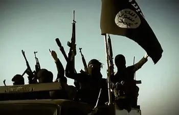 Esta imagen de archivo tomada de un video de propaganda publicado el 17 de marzo de 2014 por al-Furqan Media del Estado Islámico de Irak y el Levante (EIIL) supuestamente muestra a combatientes del EIIL levantando sus armas mientras están parados en un vehículo. montado con la bandera de los yihadistas en un lugar no revelado en la provincia de Anbar.