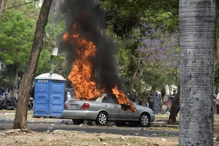 Un automóvil arde en llamas frente al Congreso Nacional, durante los enfrentamientos entre Policías y manifestantes contra el recrudecimiento de las penas a invasores de propiedades.