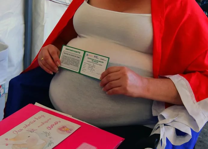 Una mujer embarazada muestra su certificado de vacunación contra el covid.
