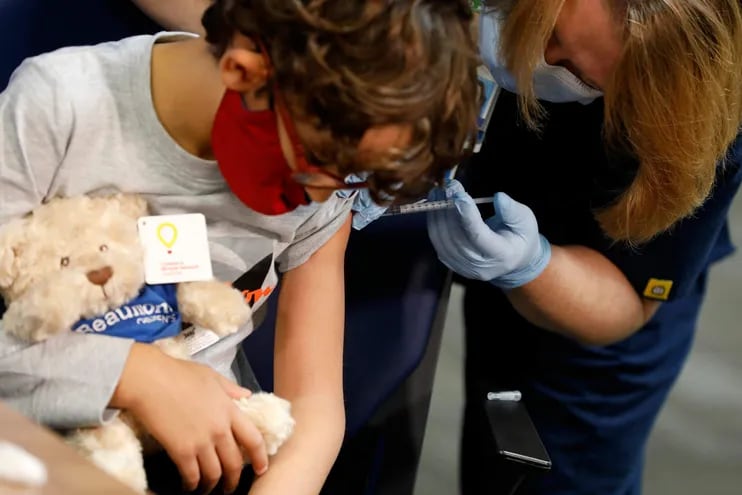Un niño de siete años se aferra a su oso de peluche mientras recibe la primera dosis de la vacuna Pfizer contr ael Covid-19 en las oficinas sanitarias de Beaumont, en Southfield, Michigan.