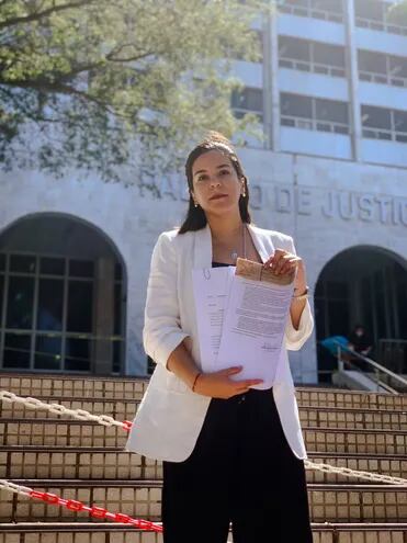 Johanna Ortega, candidata a la intendencia de Asunción frente al Palacio de Justicia exhibiendo los documentos del amparo presentado previamente.