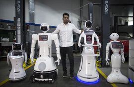 Aswin Sarang, directivo de Reliable Robotics, posa junto a robots que detectan fiebre e higieniza manos en Dubai, Emiratos Árabes Unidos.