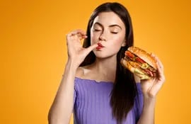 Mujer comiendo hamburguesa.