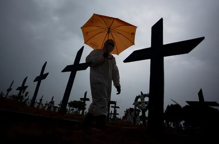 Una persona con un traje de protección biológica camina junto a las tumbas de víctimas de covid-19 en el cementerio Nossa Senhora Aparecida de Manaus, Brasil.