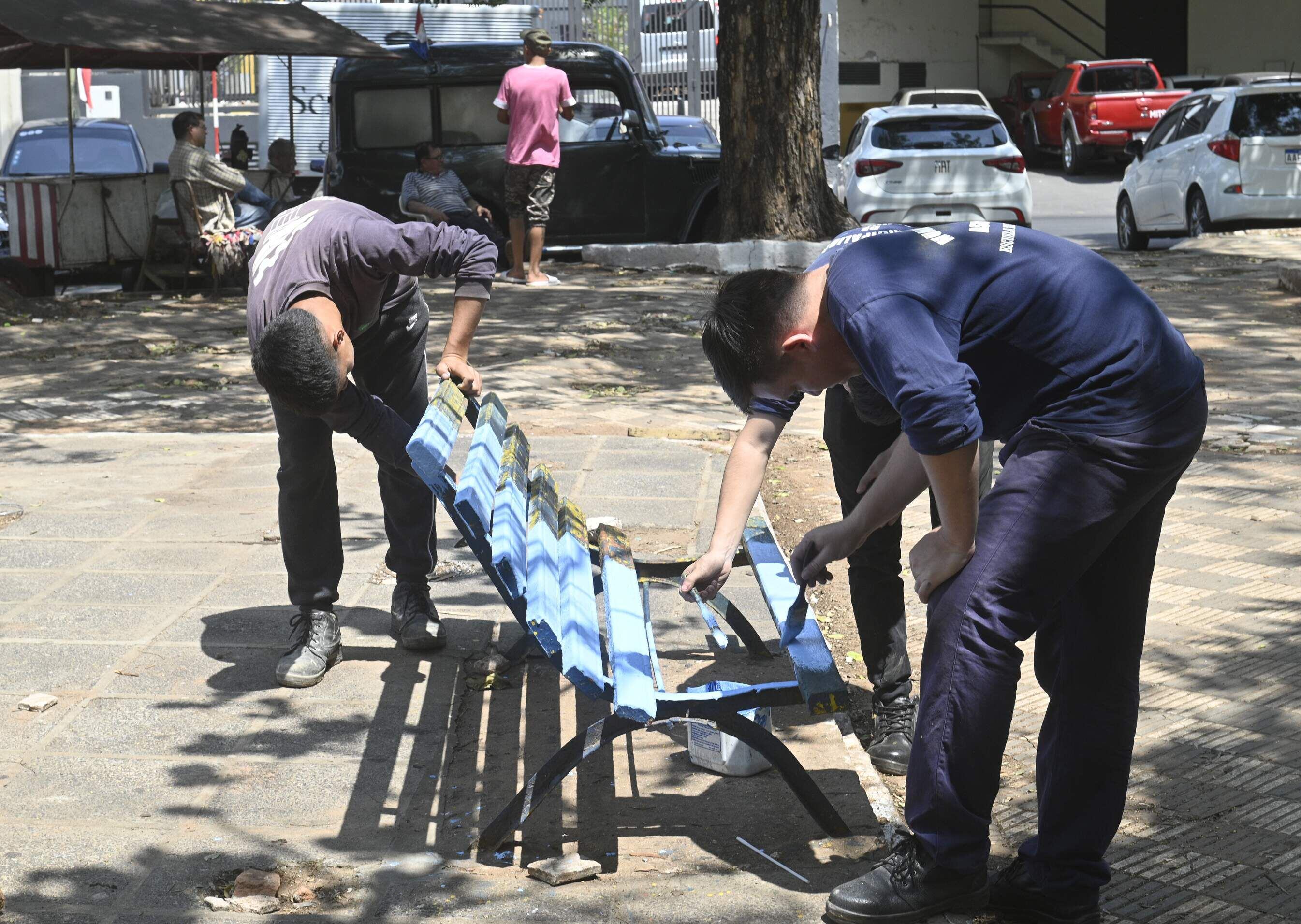 Jóvenes pintan un banco roto en la plaza Independencia - Constitución, frente a la Catedral Metropolitana.