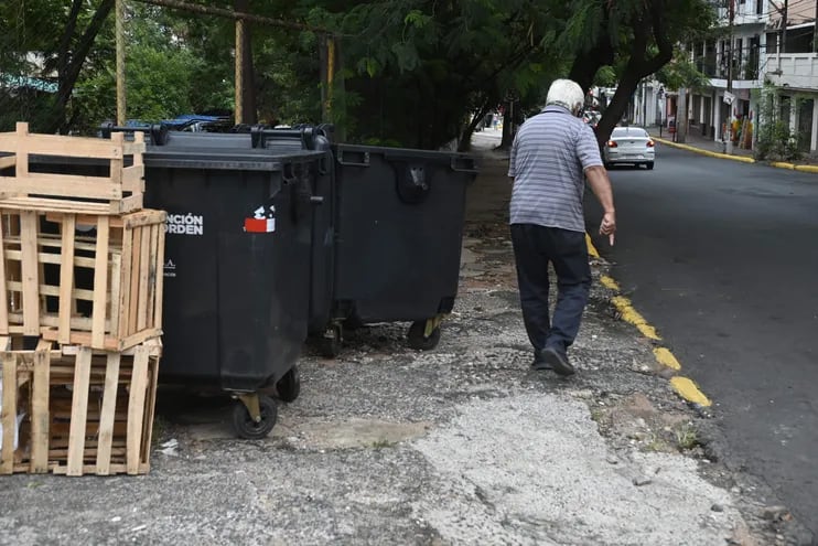 Sobre Azara y Constitución, centro de Asunción, un hombre circula con dificultad entre las veredas rotas, cajas y contenedores municipales.