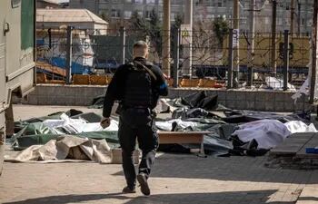 Un policía ucraniano patrulla la zona donde fueron encontrados los cuerpos de civiles tras el ataque con misil en la estación de trenes en el Donbás. (AFP)