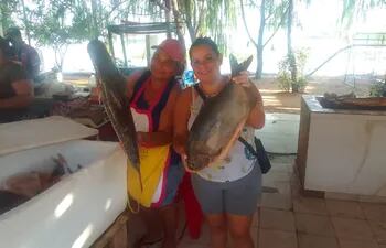 Dos comerciantes de Remanso muestran un pescado surubí y un pacú, que ofrecen por Semana Santa.