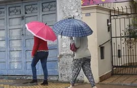 Dos mujeres con paraguas caminan bajo la lluvia en una calle de Asunción.