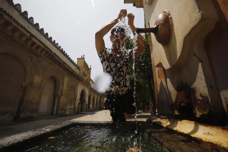 Un joven se refresca en una fuente de del Patio de los Naranjos de la Mezquita-Catedral de Córdoba, España.