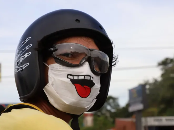 Con humor es mejor. Un motociclista sobre la ruta Transchaco, en Mariano Roque Alonso, usa un barbijo con el diseño de una boca sacando la lengua.