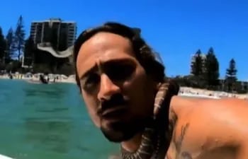 El surfista Higor Fiuza en una captura de pantalla sufeando con una serpiente pitón enroscada al cuello. El deportista recibió una multa de USD 1.500.
