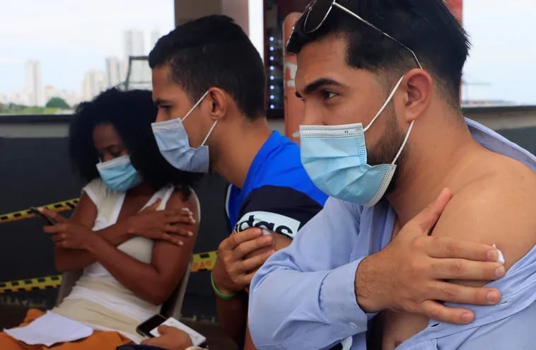 Tres jóvenes esperan tras recibir una dosis de la vacuna contra la covid-19, en Cartagena (Colombia).