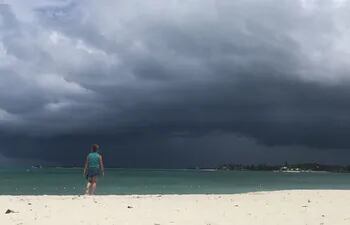 Una mujer observa una tormenta en la distancia, en una playa de Nassau, Bahamas.