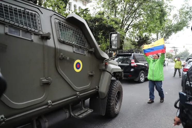 Un hombre exhibe una bandera mientras pasa un vehículo blindado donde es trasladado el exvicepresidente ecuatoriano Jorge Glas, este sábado en Quito (Ecuador).