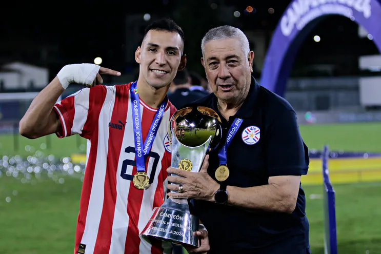 Marcos Fernández (i) y Carlos Jara Saguier, jugador y entrenador de la selección paraguaya, festejan con el trofeo de campeón del Preolímpico 2024 en el estadio Brígido Iriarte, en Caracas, Venezuela.