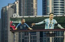 Un cartel con imágenes del delantero francés Kylian Mbappe (L) y el capitán argentino Lionel Messi se exhibe en Doha.