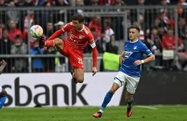 Thomas Müller, del Bayern Munich, salta en procura de controlar el balón ante la presencia de un jugador del Hoffenheim, durante el partido que empataron 1-1.