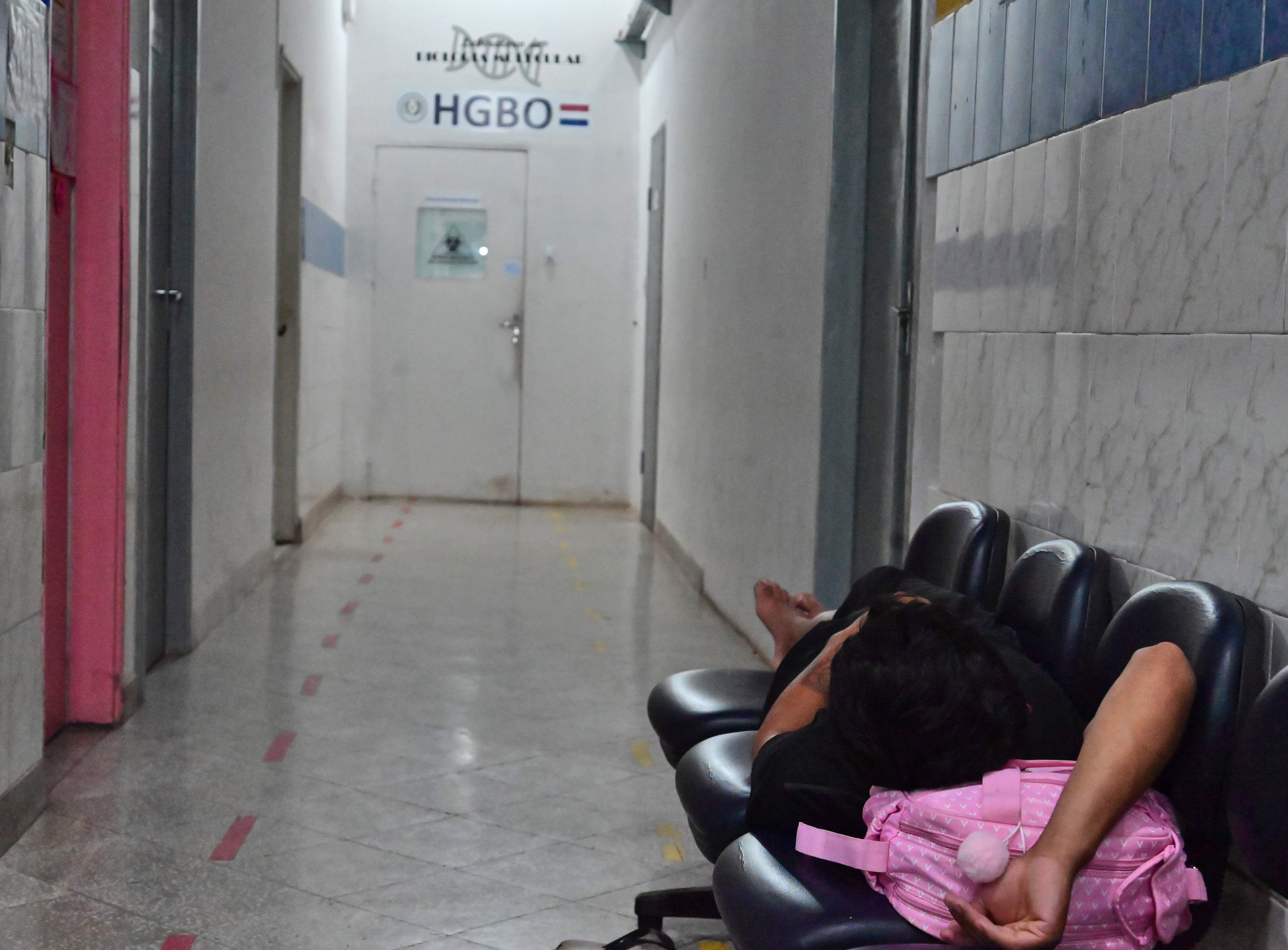 Un paciente, espera acostado por atención médica en uno de los bancos del Hospital General de Barrio Obrero. 