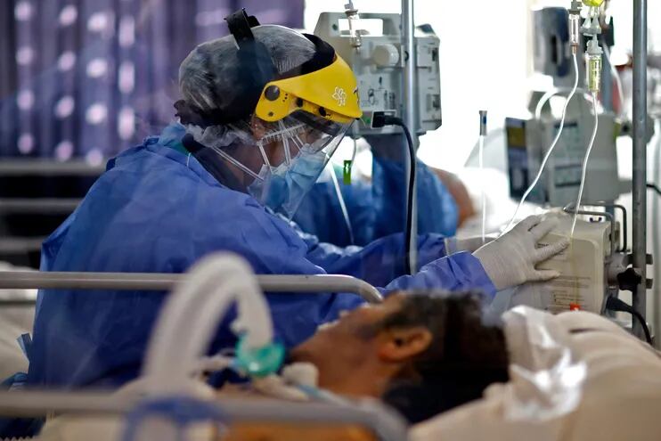Un trabajador sanitario controla el estado de un paciente con COVID-19 en la unidad de terapia intensiva del hospital San Roque Hospital en Córdoba, Argentina.