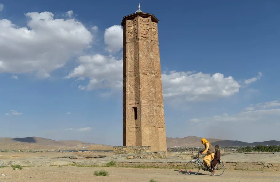 En bici, un hombre pasa junto a un minarete histórico en Ghazni.