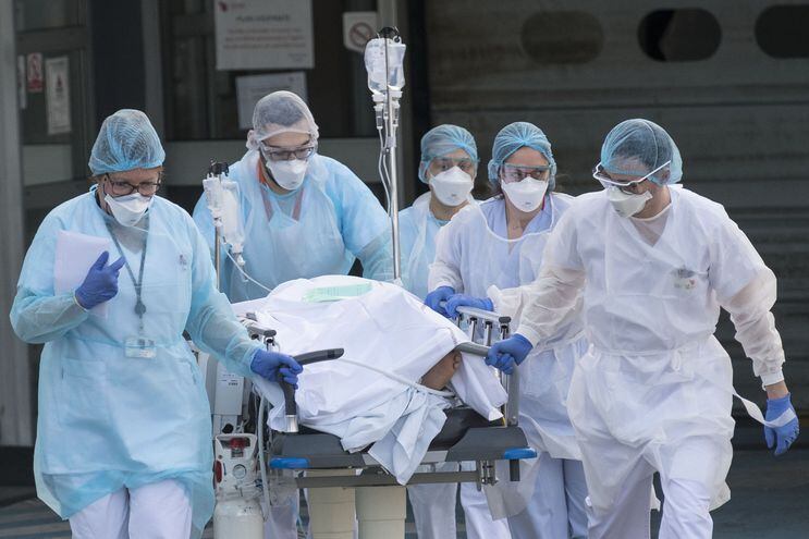 Miembros del cuerpo médico del hospital  Emile Muller, de Mulhouse, Francia, evacuan a un paciente con coronavirus que debe ser trasladado a otro hospital.
