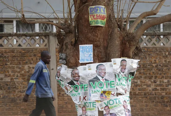 Un hombre pasa junto a los carteles de la campaña electoral del presidente de Zimbabwe, Emmerson Mnangagwa, en Harare.