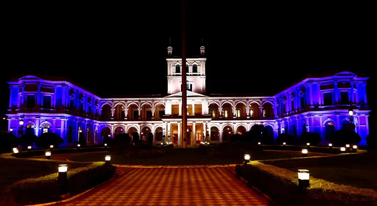 En la fotografía al fondo se ve el Palacio de Gobierno que en su lado izquierdo está iluminado con azul, en el centro blanco y a la derecha nuevamente azul; siendo estos los colores de la Bandera de Israel.