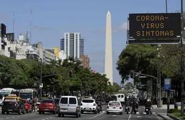 Un cartel de tráfico despliega un mensaje sobre los síntomas que puede provocar el coronavirus, sobre la avenida 9 de Julio, en Buenos Aires. De fondo se ve el Obelisco.
