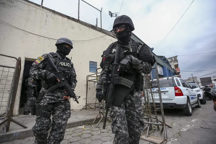 Integrantes de la policía nacional de Ecuador esperan, frente a la cárcel de El Inca, en Quito (Ecuador). Las bandas narcos se enfrentan en plena vía pública.  (EFE)
