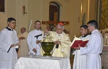 El cardenal Adalberto Martínez derrama perfume sobre uno de los óleos que bendijo.