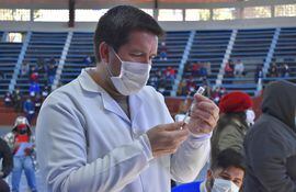 El personal de blanco del Hospital Regional de Villarrica, Lic. Victor Rufinelli, preparando la dosis del antiviral.