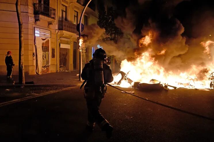 Un bombero intenta apagar las llamas en una calle de Barcelona donde se registraron enfrentamientos entre manifestantes y la policía, este jueves.