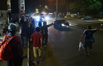Decenas de pasajeros esperan por un colectivo en la noche del martes 30 de marzo sobre la avenida Fernando de la Mora, en Asunción. Algunos claman por la parada saliendo inclusive sobre el asfaltado.