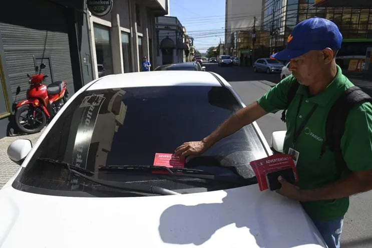Funcionario de Parxin coloca advertencia a vehículo estacionado sin pagar.