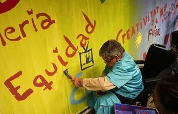 Personas con discapacidad participan en una pintada de un mural colectivo de más de 20 metros.