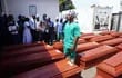 Un trabajador de la salud se encuentra entre los ataúdes de los veintisiete manifestantes y seis policías, antes de un entierro masivo en Freetown el 17 de octubre de 2022.