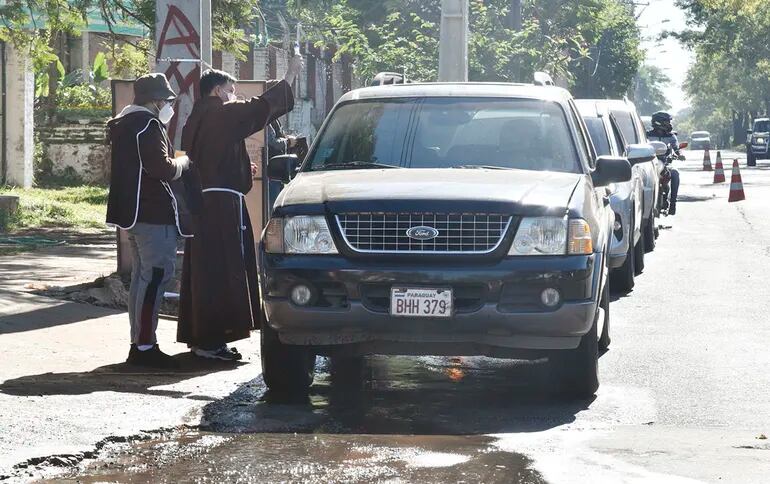 Uno de los hermanos capuchinos, con el hisopo en la mano, asperja con agua bendita el vehículo al tiempo de orar por sus ocupantes.