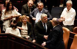 El ministro de Exteriores Yair Lapid (2do. de la der.) saluda al primer ministro saliente, Naftali Bennett, luego de la disolución del Parlamento (Knesset), en Jerusalem.  (AFP)