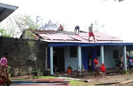 Hombres reparan el techo de una casa después del paso del ciclón Freddy en Mananjary.