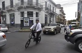 En una bicicleta eléctrica y tocado con un casco, este ciclista cruza la calle Palma, en el microcentro de Asunción.