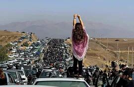 Esta imagen UGC publicada en Twitter supuestamente el 26 de octubre de 2022 muestra a una mujer revelada de pie sobre un vehículo mientras miles se dirigen hacia el cementerio de Aichi en Saqez, la ciudad natal de Mahsa Amini en la provincia occidental iraní de Kurdistán, para marcar 40 días desde Su muerte, desafiando las estrictas medidas de seguridad como parte de una sangrienta represión de las protestas lideradas por mujeres.