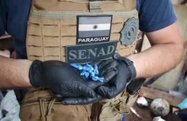 Agente de la SENAD sostiene las dosis de chespi o crack incautadas durante allanamiento a la "Chespi Roga".