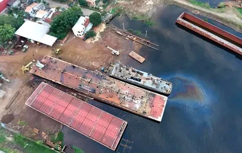 Se puede ver la mancha del hidrocarburo en el agua, donde los operarios del astillero del diputado Bachi Núñez y su mujer limpian, reparan y desguazan embarcaciones.
