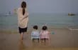 Una mamá y sus dos hijos miran el mar en la playa de Sokcho, en Corea del Sur. Los chicos están listos para volver a las clases.