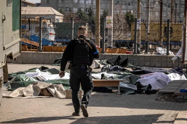 Un policía ucraniano patrulla la zona donde fueron encontrados los cuerpos de civiles tras el ataque con misil en la estación de trenes en el Donbás. (AFP)