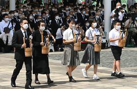 Sobrevivientes de la bomba atómica y representantes de familias afectadas llevan ofrendas de agua durante una ceremonia de conmemoración en el Parque de la Paz en Nagasaki, este martes.