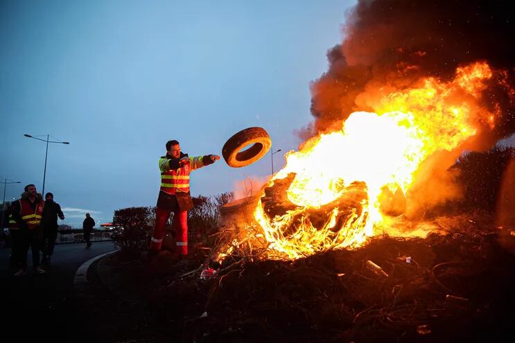 Un manifestante lanza una cubierta de neumático a una fogata al costado de una ruta en Le Havre, Francia, este martes.