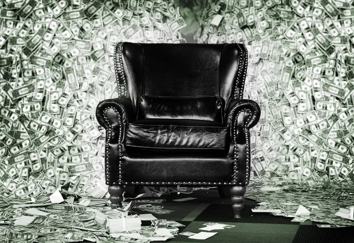 Un sillón de cuero negro rodeado de billetes de dólares.